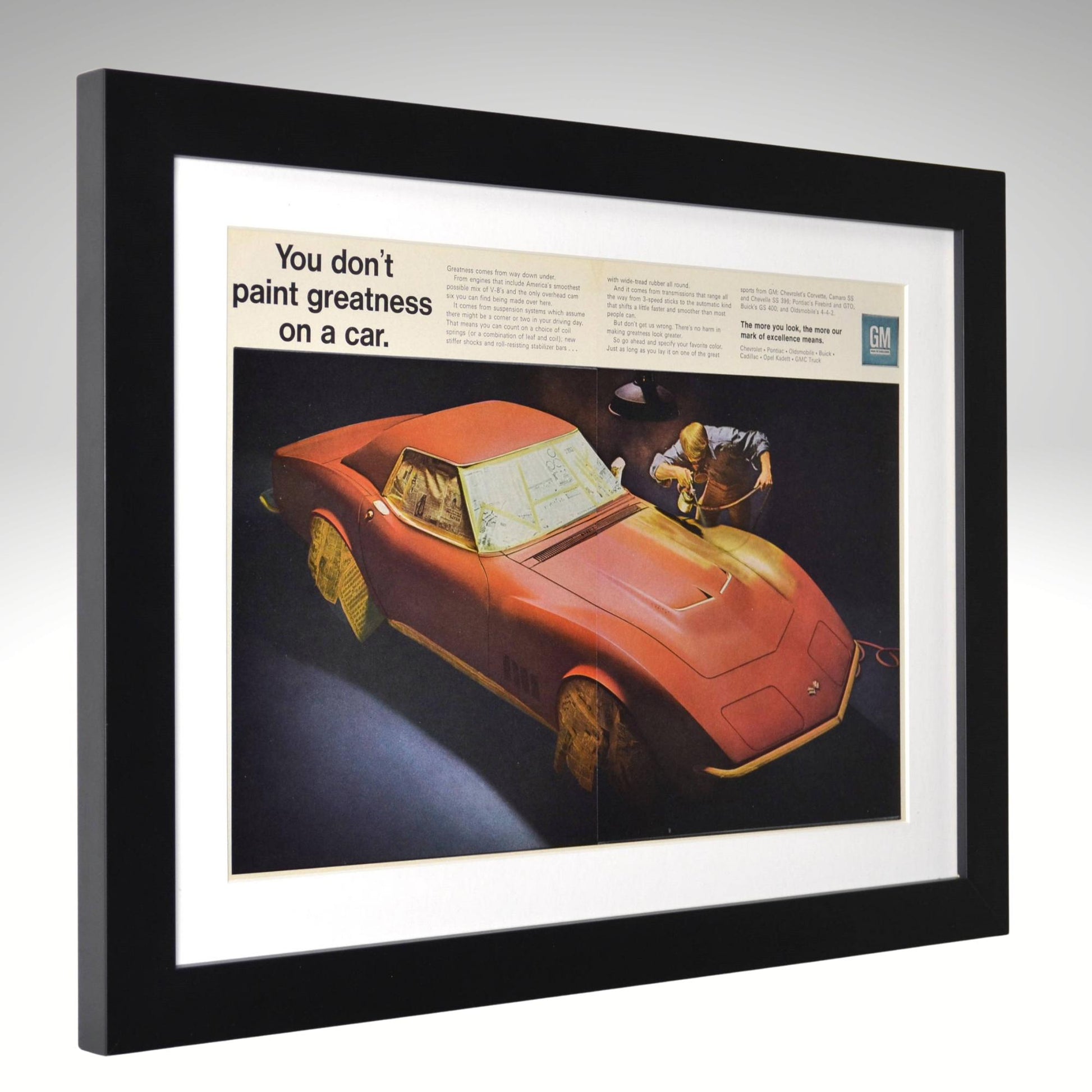 Framed 15x20 vintage 1969 GM Corvette two-page print ad showing a Corvette masked with newspaper during paint prep — classic automotive wall art side view
