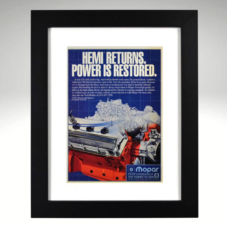 Framed vintage Mopar ad featuring the return of the 426 HEMI crate engine, bold blueprint-style design with Chrysler’s iconic orange block, 12x15 print.

