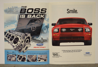 Ford advertisement with a red Mustang and engine parts, featuring text 'The Boss is Back' and 'Smile.'