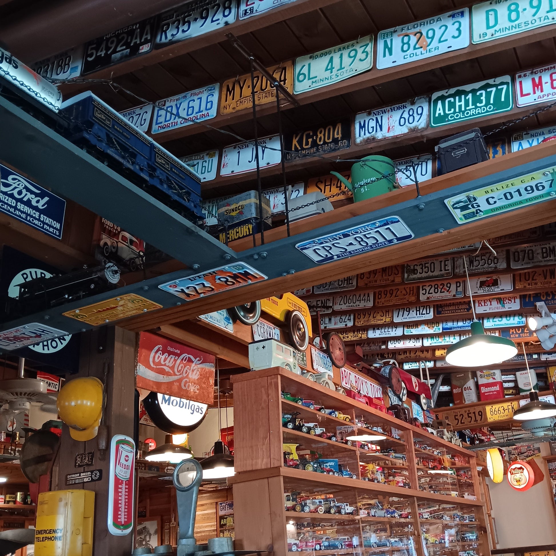 Large collection of authentic vintage embossed license plates displayed across garage walls with classic automotive decor