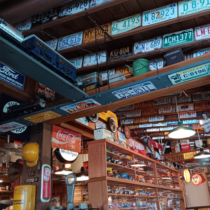 Large collection of authentic vintage embossed license plates displayed across garage walls with classic automotive decor