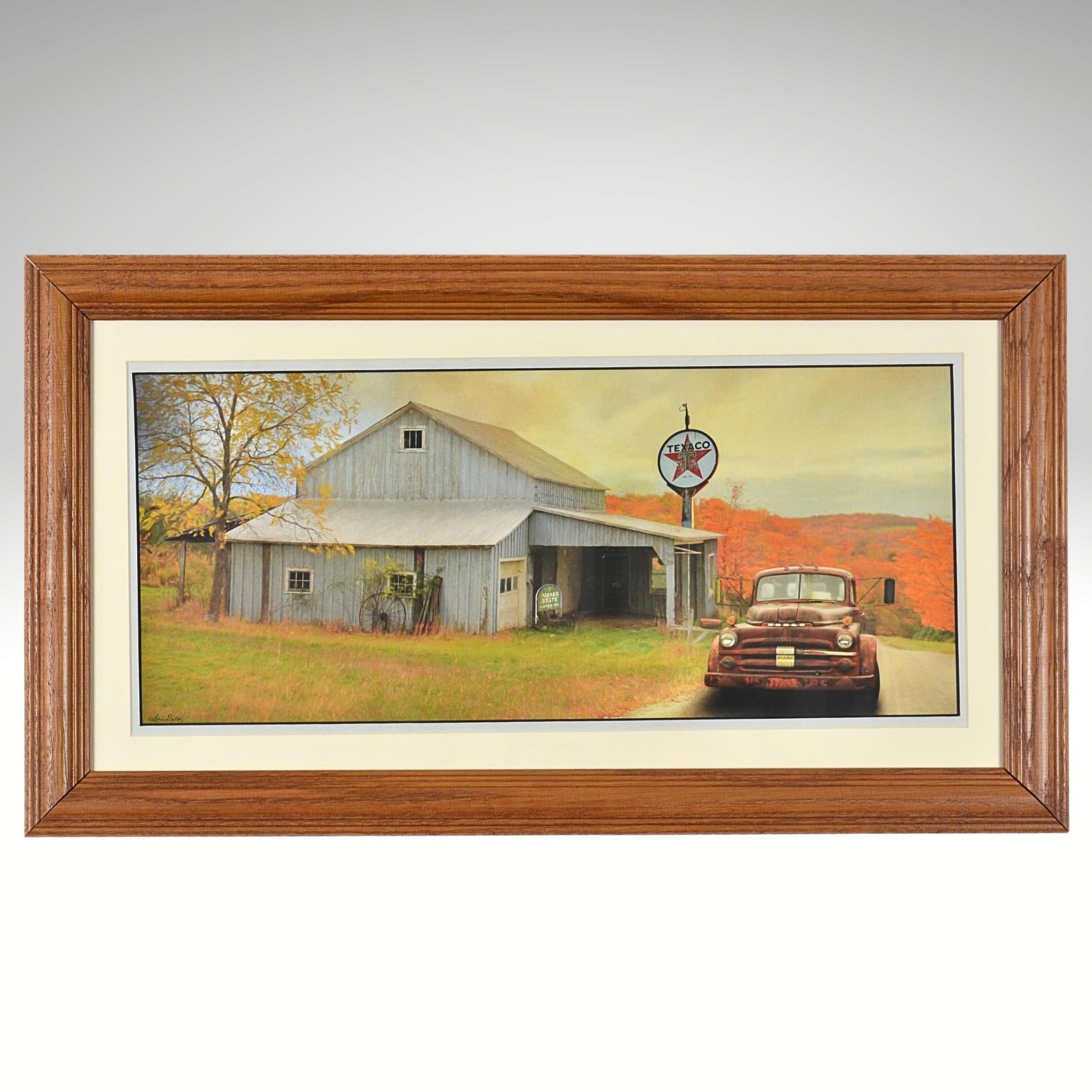 Framed artwork of a barn and vintage car with a texaco sign in the background.