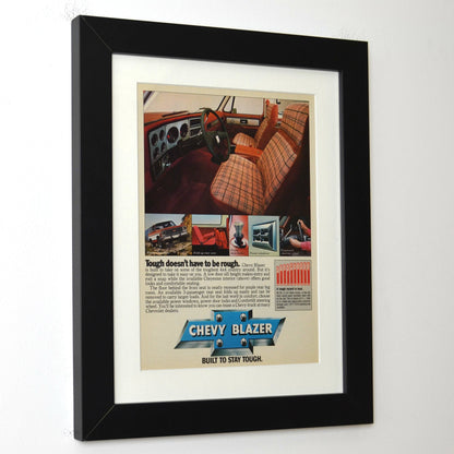 Framed vintage advertisement for Chevrolet Blazer showing car interior and branding.