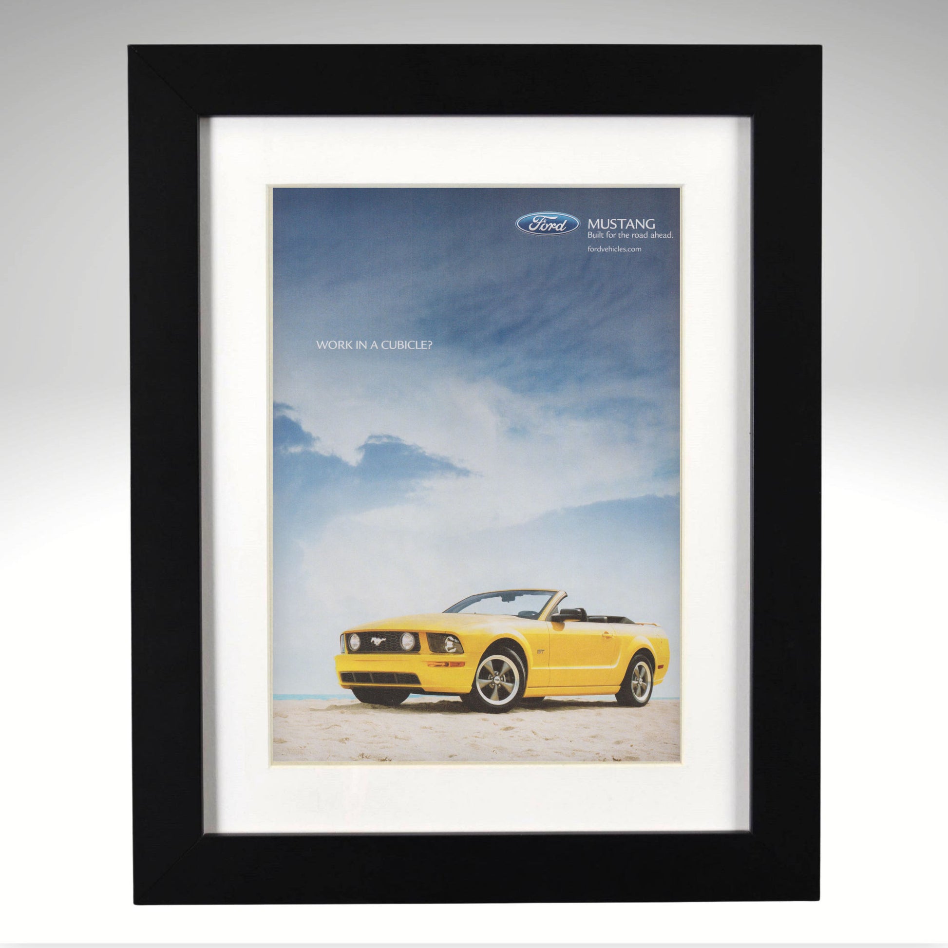 Framed poster of a yellow Ford Mustang convertible against a blue sky with clouds.