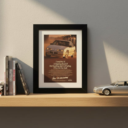 A framed vintage Pontiac Grand Prix SE advertisement print, featuring a white sports car on a warm sunset road with the headline 'Grand Prix SE' and smaller text below, set in a black frame with a white mat against a light gray background.
