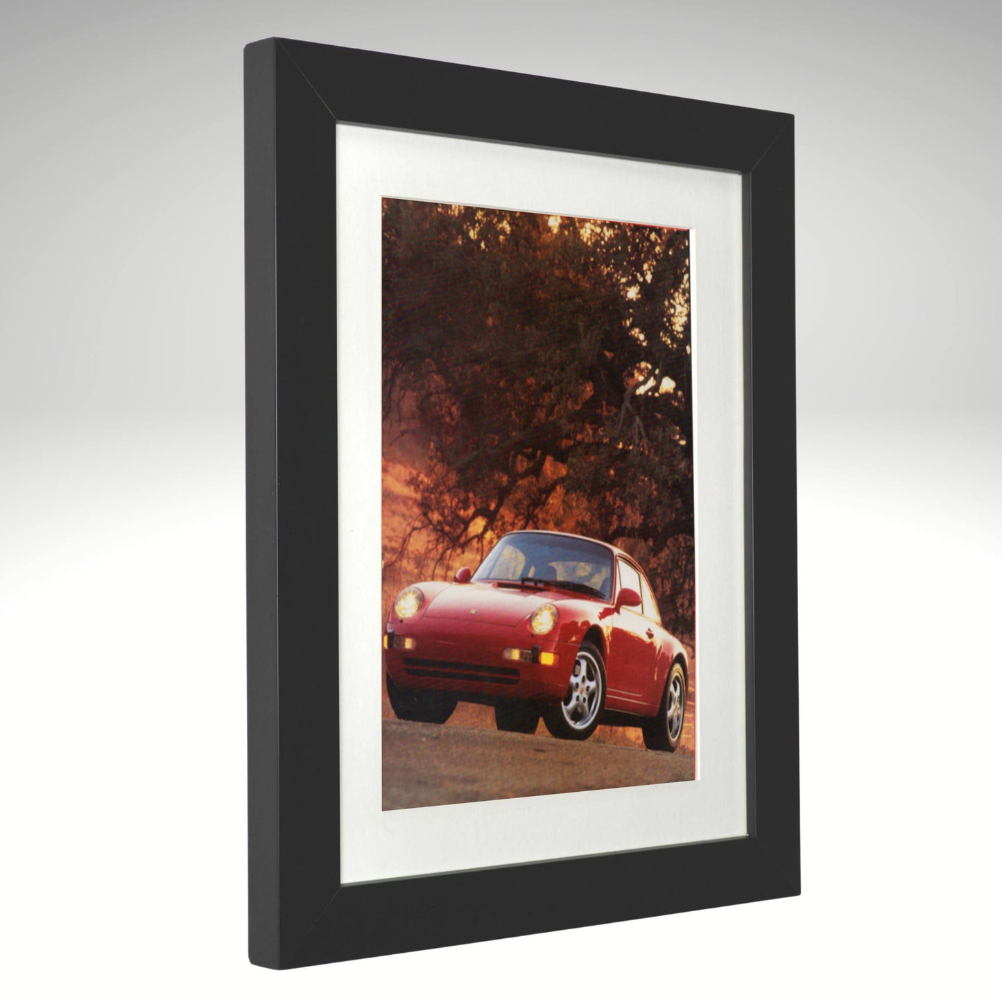 Framed photograph of a red Porsche Boxster in a forest setting